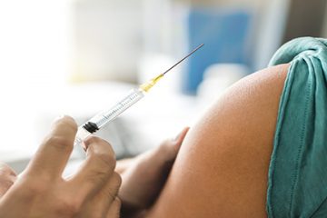 Vaccine or flu shot in injection needle. Doctor working with patient's arm. Physician or nurse giving vaccination and immunity to virus, influenza or HPV with syringe.