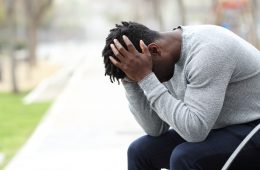 Sad depressed black man on a bench in a park