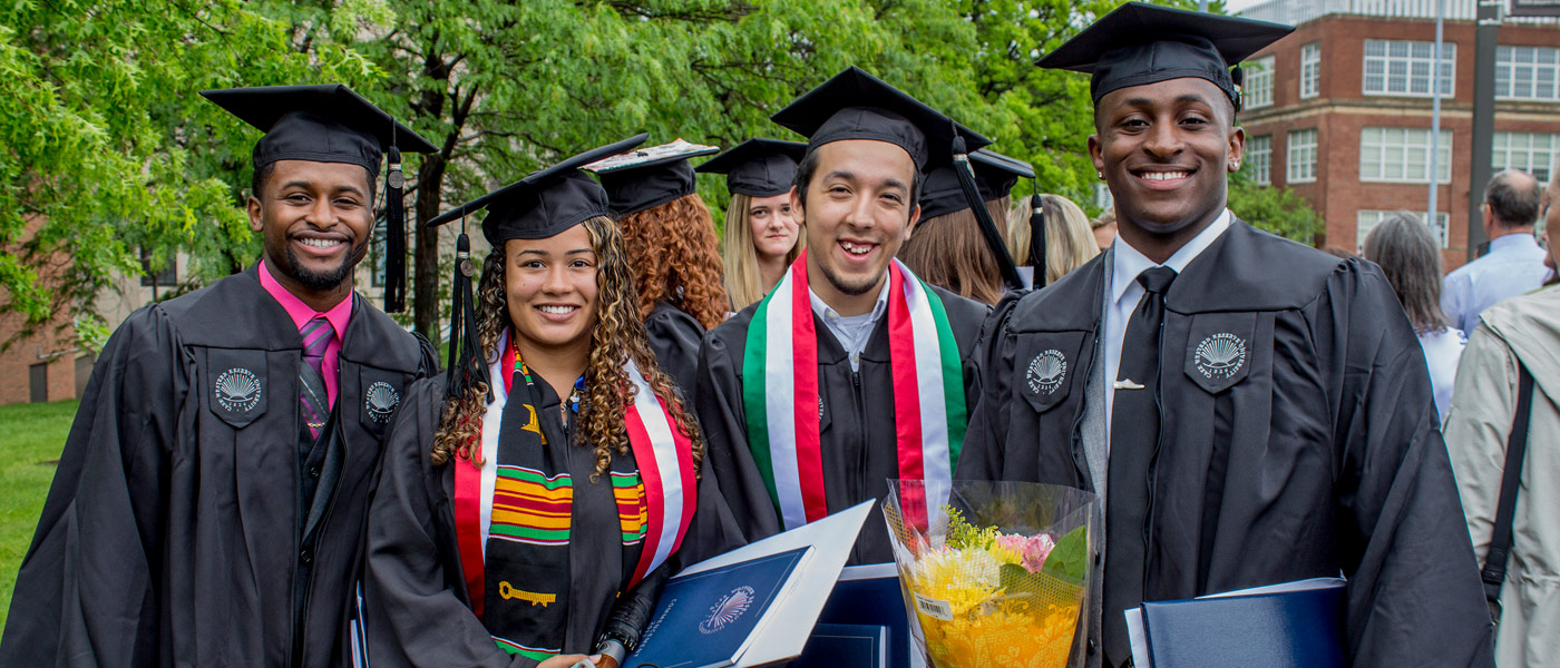 Photo of four graduates posing for a photo at commencement