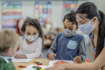 Group of children colouring while wearing masks