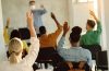 Rear view of college students raising hands to answer teacher's question during a lecture.