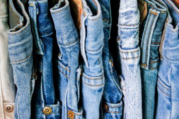 Photo showing different shades of denim blue jeans aligned closely on a rack