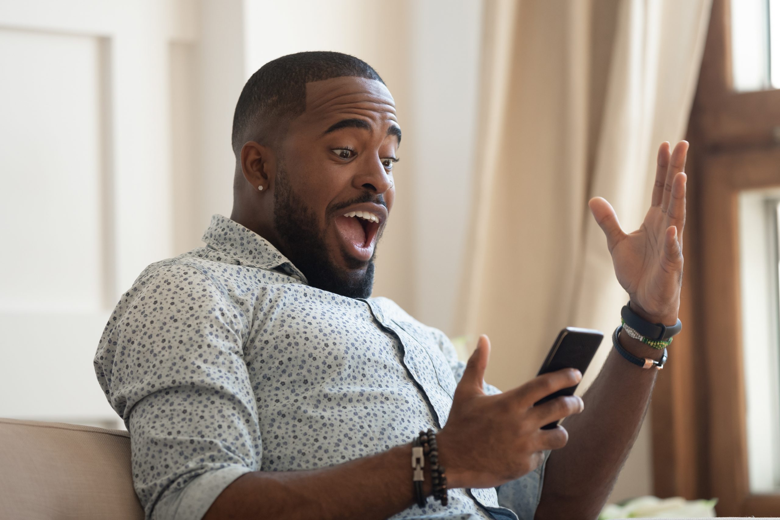 Surprised man ooking at cellphone read good news