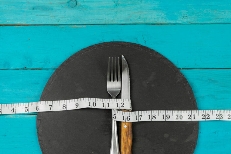 A fork and knife on a plate wrapped up in a measuring tape