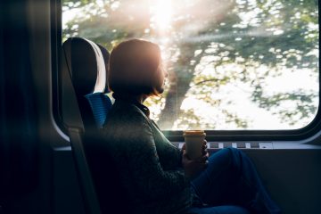 A middle aged woman sitting by the window of a commuter train