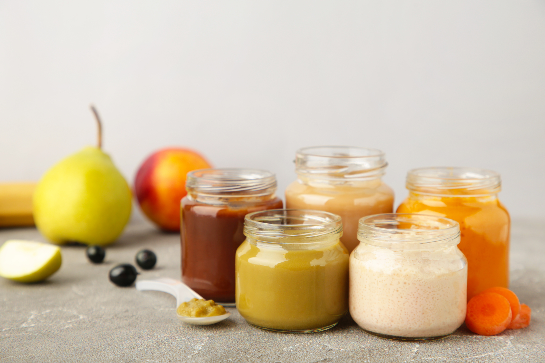 Glass jars with nutrient baby food on grey background