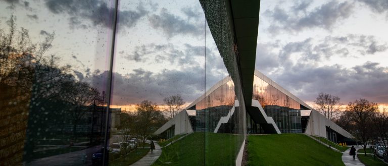 Photo of the Tinkham Veale University Center covered in rain droplets on the windows and clouds reflected onto the windows