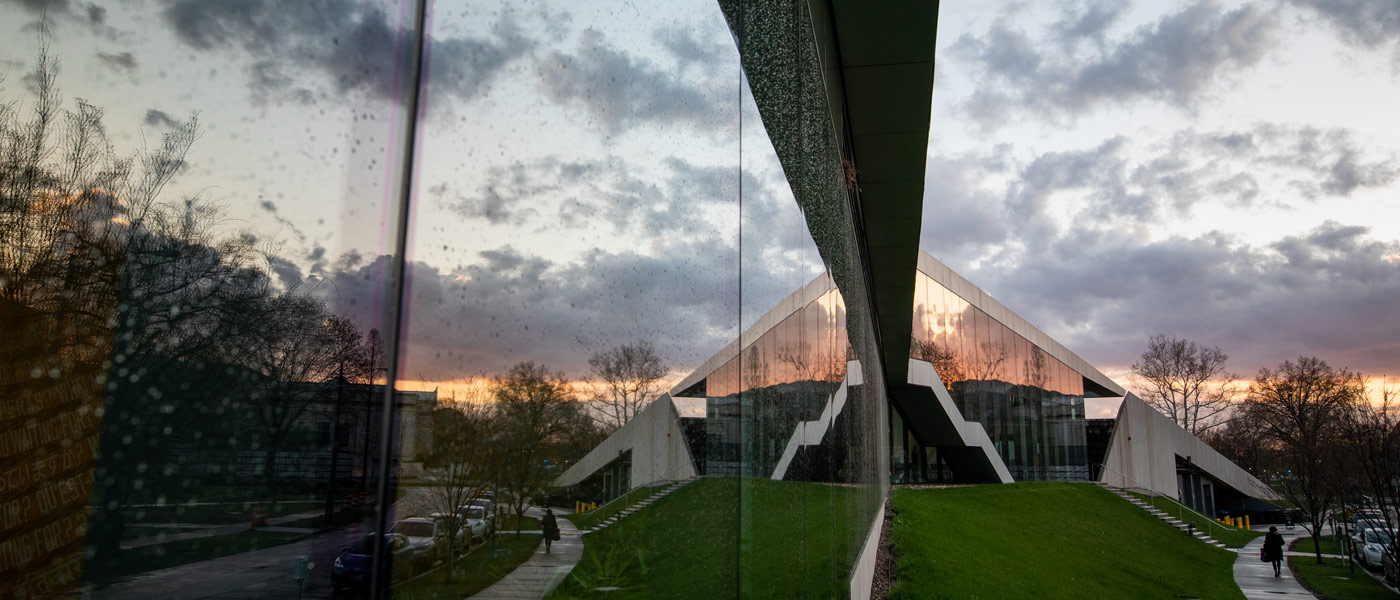 Photo of the Tinkham Veale University Center covered in rain droplets on the windows and clouds reflected onto the windows