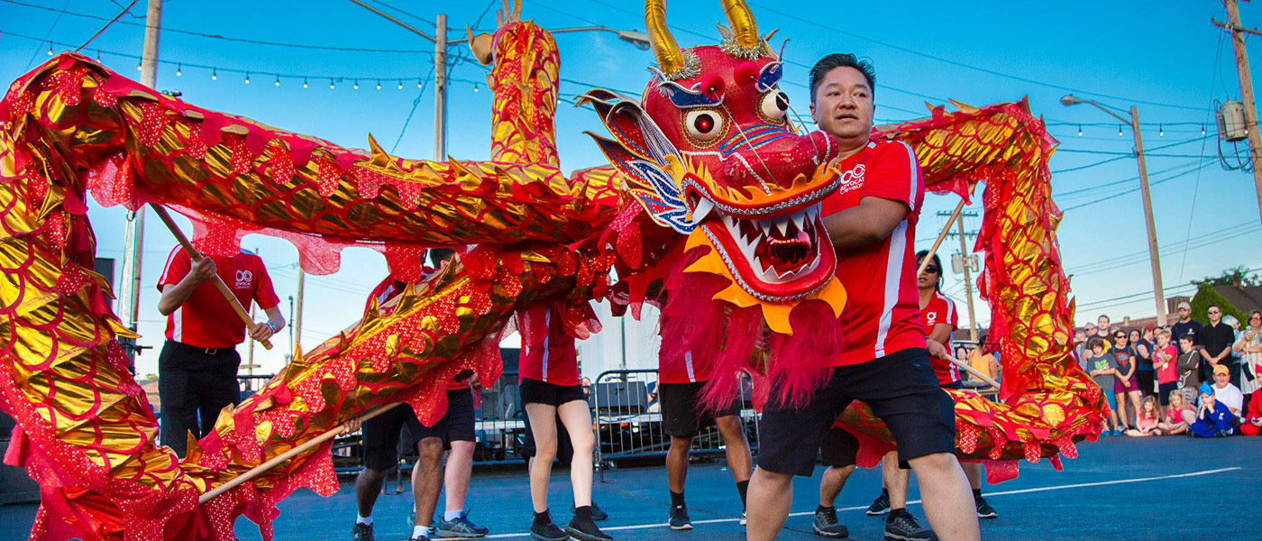 Photo of Wayne Wong holding the head of a dragon puppet during a festival dance