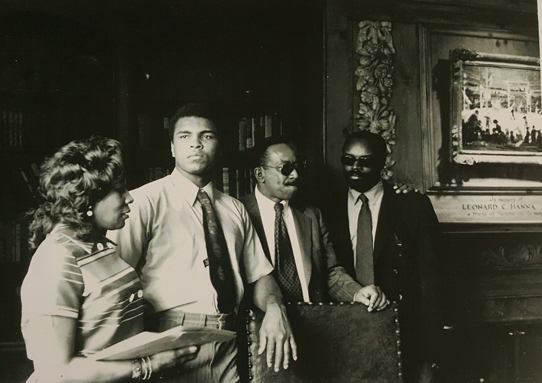 Black and white photo of Muhammad Ali visiting the Hanna Lounge as others stand nearby him