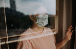 an asian chinese female looking out from her balcony window with her face mask during the restricted movement order in malaysia