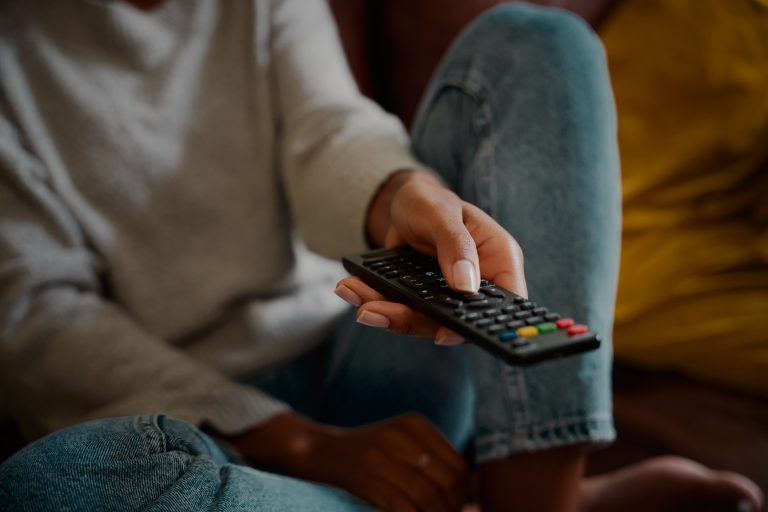 Woman hand holding television remote at home