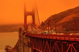 Cars crossing Golden Gate Bridge from Lime point. Smoky orange sky the bridge of San Francisco city for California fires in America. Wildfires composition.