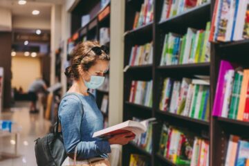 Woman choosing a new book in the bookstore during COVID-19 pandemic