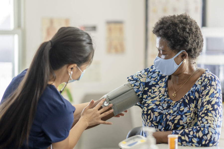 Female medical professional checking senior patient's blood pressure