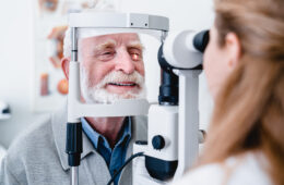 Smiling cheerful elderly patient being checked on eye by female ophthalmic doctor