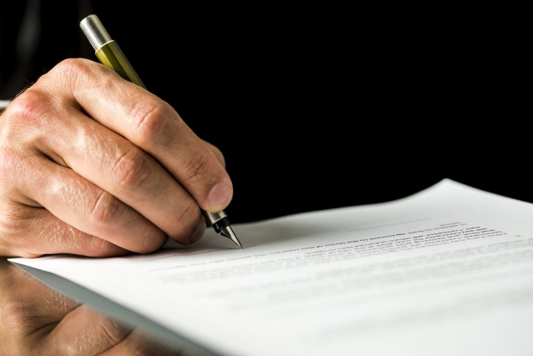 Male hand signing a contract, employment papers, legal document