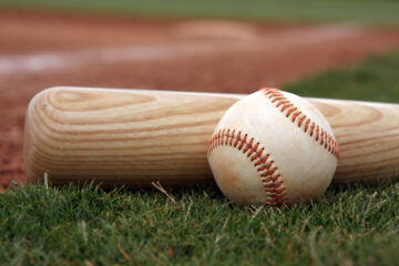 Close-up if baseball and bat resting on the field