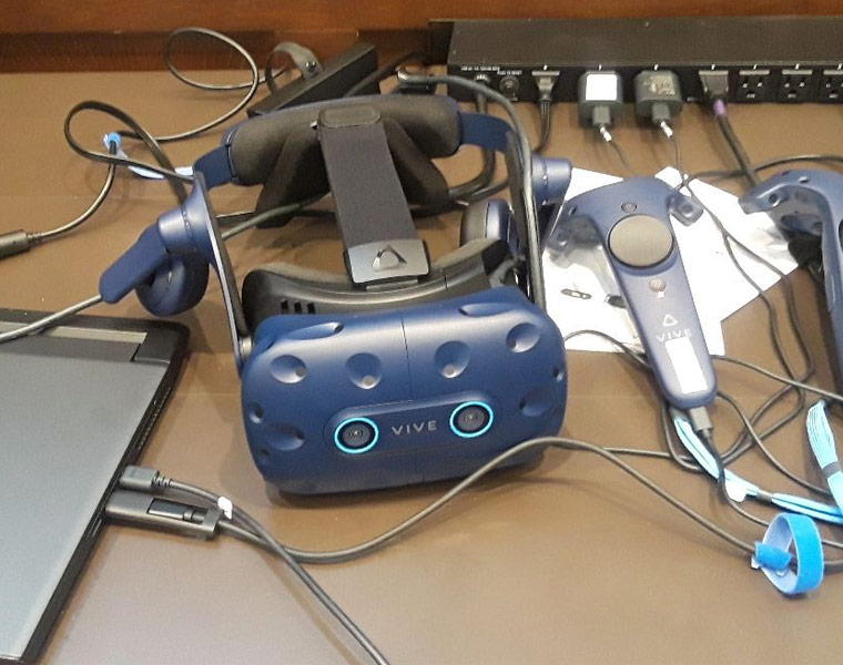 Photo of the VR headset and controllers on a desk with other tech equipment