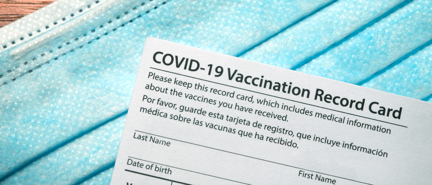 Photo of a blank vaccination card on top of a mask