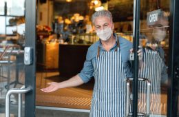 Business owner wearing a facemask and reopening his cafe after the quarantine