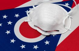 Ohio state flag and N95 face mask. Concept of state and local government face covering mandate, order, requirement and social distancing during Covid-19 coronavirus pandemic