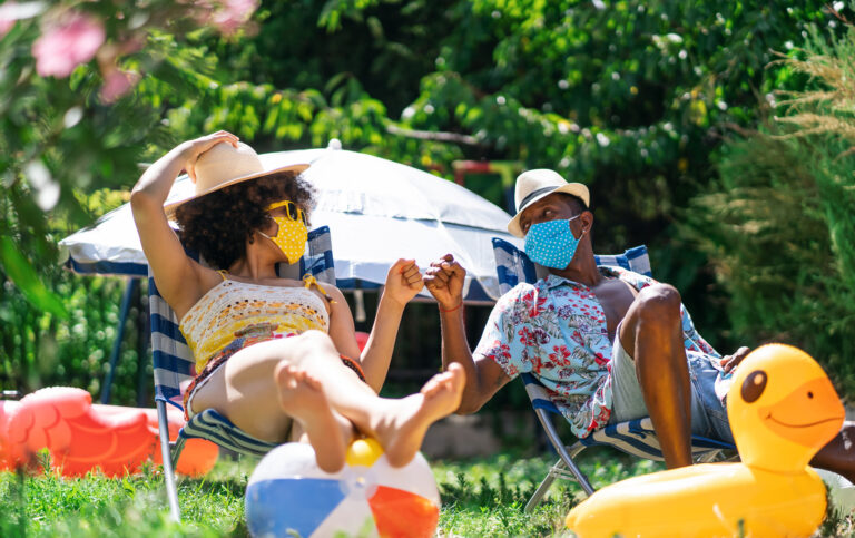Afro Couple wearing protective face mask having staycation fun on back yard and practicing alternative greeting, during COVID-19