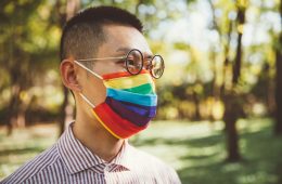 Young man wearing gay pride mask