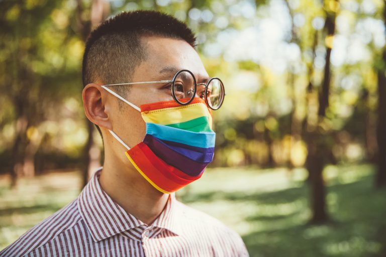 Young man wearing gay pride mask