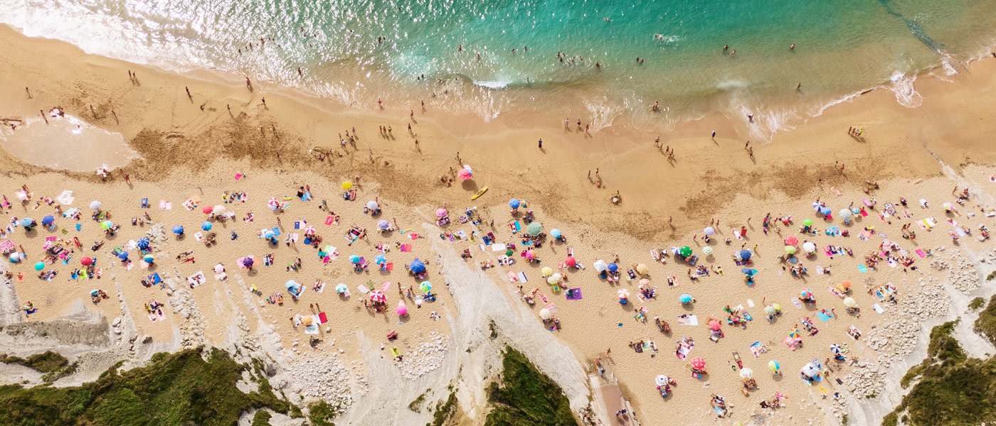Aerial photo of beachgoers with colorful towels and umbrellas on a beach near the sea