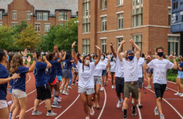 Photo of new students running through a tunnel of orientation leaders on the track during a Discover Week event
