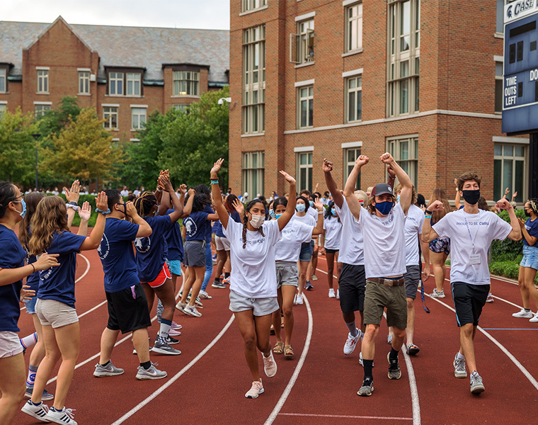 Photo of new students running through a tunnel of orientation leaders on the track during a Discover Week event