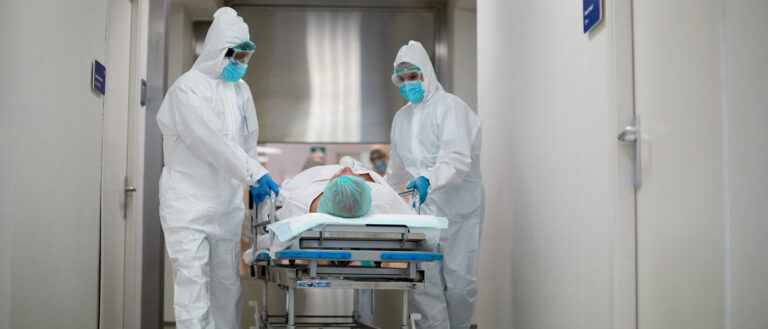 Photo of health care workers in PPE transferring a patient from the emergency area into the ICU