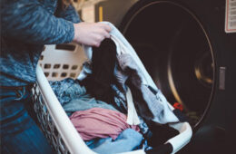 Close up photo showing someone loading laundry from a basket into a machine