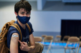Photo of a student pointing to a bandage on his arm at the CWRU vaccine clinic