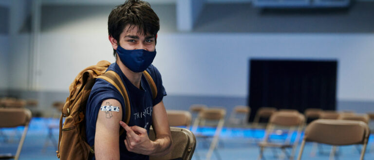 Photo of a student pointing to a bandage on his arm at the CWRU vaccine clinic