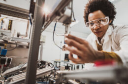 Photo of a woman working with high-tech manufacturing machinery.