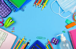 School supplies and COVID 19 prevention frame on a blue paper background
