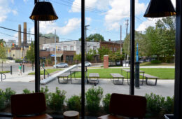 Photo looking out from the large windows of Fribley Commons showing the view of campus and an outdoor seating area