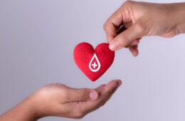 Photo of someone placing a heart icon with a donation symbol on it in someone else's hand
