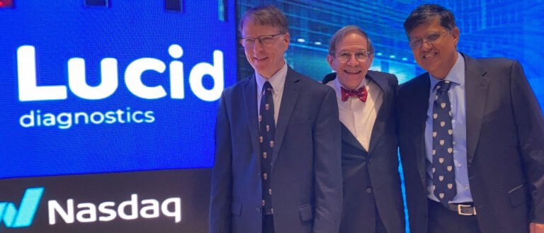 Photo of the three Lucid Diagnostics founders posing for a photo in front of a digital sign that says "Lucid Diagnostics" and "Nasdaq"