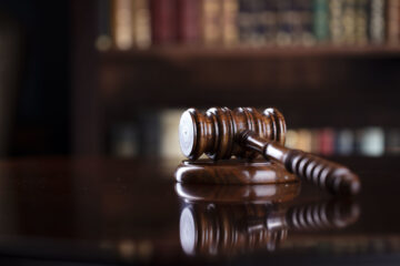 Photo of a gavel on a desk with a blurred bookcase in the background