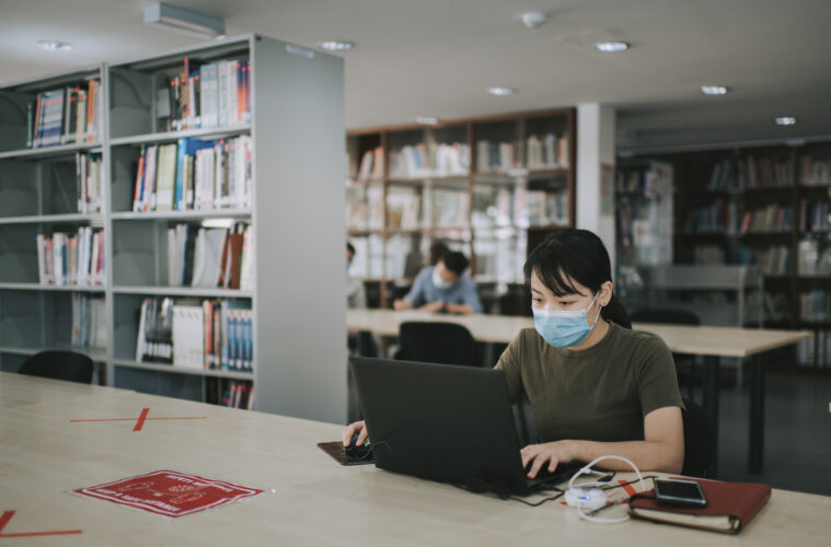 Photo of a student on a laptop at a library