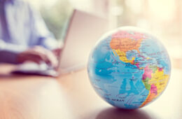 Globe on table with person on laptop in the background