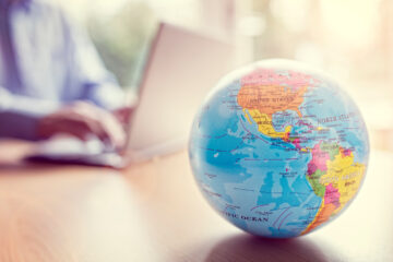 Globe on table with person on laptop in the background