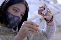An Asian American woman fills a syringe from a vial