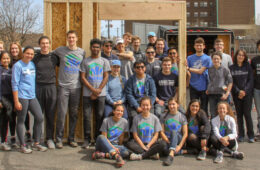 Photo of the CWRU Habitat for Humanity group posing for a photo with framing for a house
