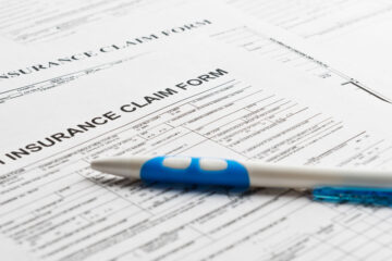 Photo of health insurance forms scattered with a pen on top