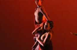 Photo of dancers holding up others in a red-tinged photo in MaDaCol dance