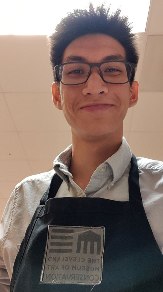 Photo of Winston Kam wearing an apron that says Cleveland Museum of Art Conservation